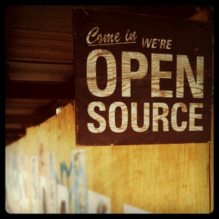 ein Schild im Stil eines alten Holzbretts mit der Aufschrift „Come in. We’re Open Source.“